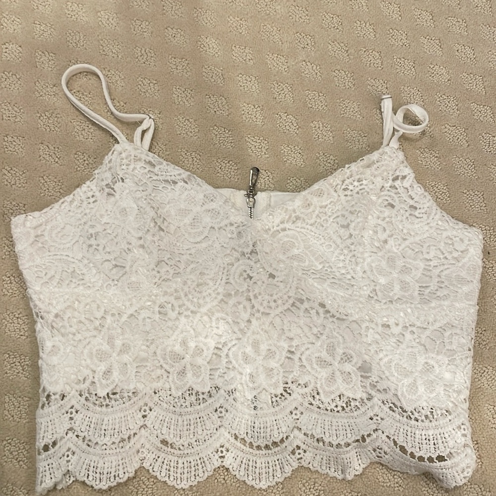 White lace crop top with spaghetti straps and a zipper closure.